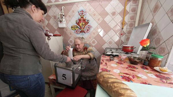 Женщина опускает бюллетень в мобильную урну для голосования в одном из домов в Харьковской области во время второго тура президентских выборов на Украине