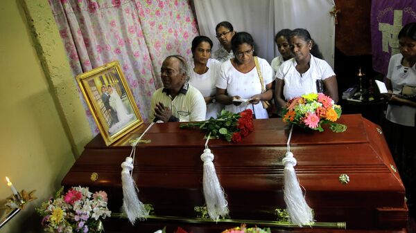 Семья скорбит рядом с гробом родственника, погибшего во время взрывов в пасхальное воскресенье в Коломбо, Шри-Ланка. 23 апреля 2019