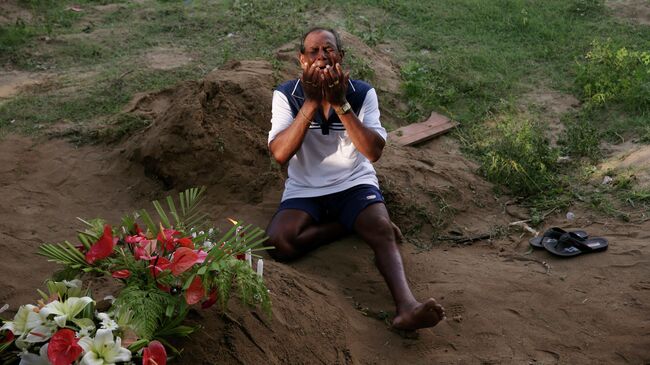 Мужчина скорбит рядом с могилой родственника, погибшего во время взрывов в пасхальное воскресенье в Негомбо, Шри-Ланка. 23 апреля 2019