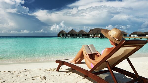 Женщина читает книгу на берегу 