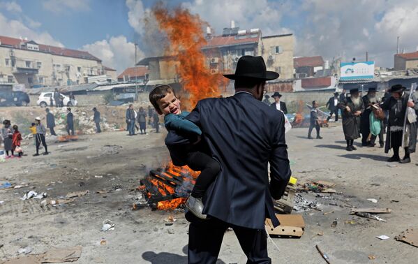 Ультраортодоксальный еврей держит ребенка во время ритуала Biur Chametz накануне Пасхи 