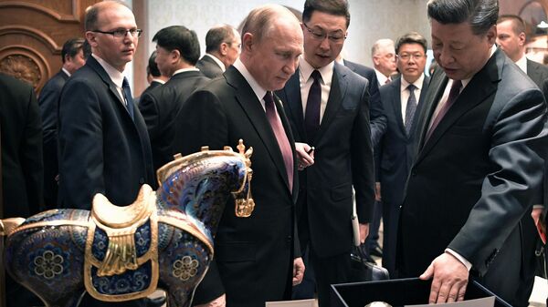 Президент РФ Владимир Путин и председатель КНР Си Цзиньпин обмениваются подарками после рабочего завтрака. 26 апреля 2019