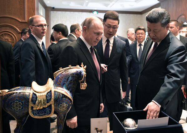 Президент РФ Владимир Путин и председатель КНР Си Цзиньпин обмениваются подарками после рабочего завтрака