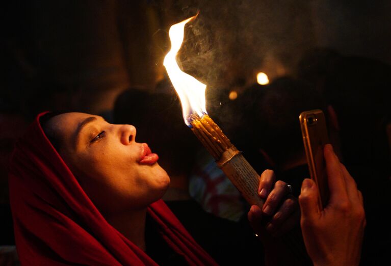Женщина празднует схождение Благодатного огня в храме Гроба Господня