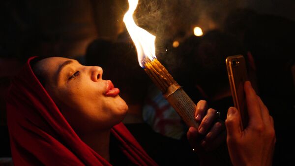 Женщина празднует схождение Благодатного огня в храме Гроба Господня