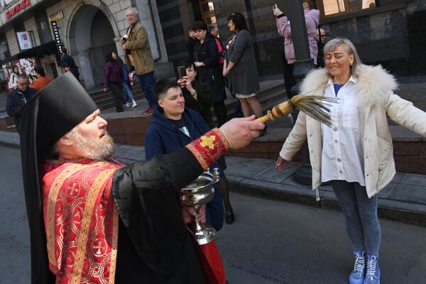 Священник освящает людей во время пасхального крестного хода во Владивостоке