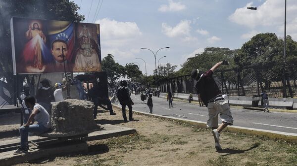 Сторонник оппозиции кидает коктейль Молотова во время столкновения с Национальной гвардией Венесуэлы в районе аэропорта Каракаса