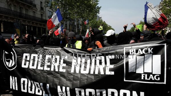 Протестующие в масках на традиционной рабочей первомайской демонстрации в Париже, Франция. 1 мая 2019 