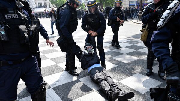 Полицейские задерживают демонстранта на первомайской демонстрации в Париже. 1 мая 2019