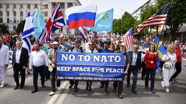 Представители зарубежных стран несут транспарант с надписью Нет НАТО во время первомайского шествия в Симферополе