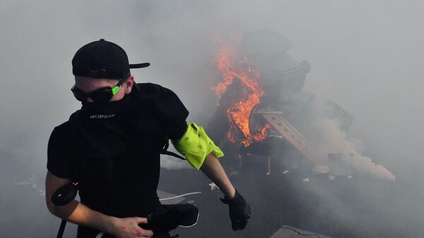 Участник уличных беспорядков у горящей баррикады на улице Парижа