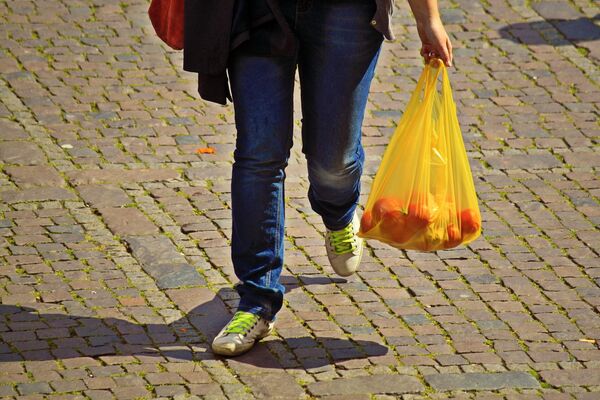 Покупатель с продуктами в пластиковом пакете Покупатель с продуктами в пластиковом пакете