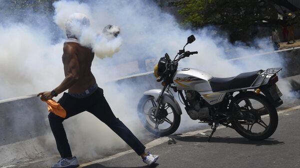 Протестующий кидает бутылку со слезоточивым газом во время столкновения с Национальной гвардией Венесуэлы в Альтамире, районе Каракаса.  Архивное фото
