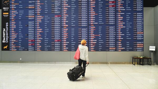 Женщина возле информационного табло с расписанием рейсов в аэропорту Шереметьево