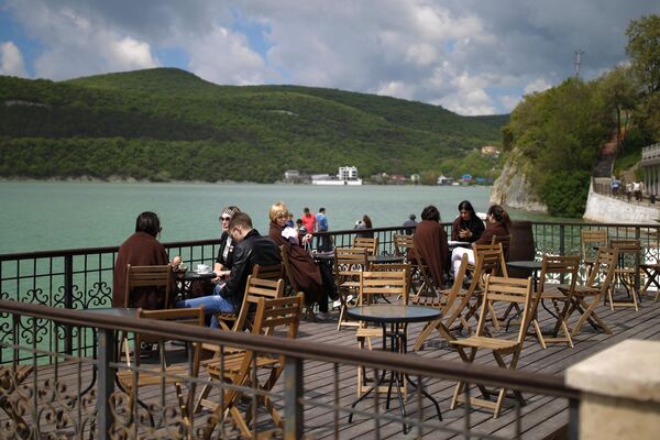 Отдыхающие на террасе летнего кафе в селе Абрау-Дюрсо на берегу озера Абрау в Краснодарском крае
