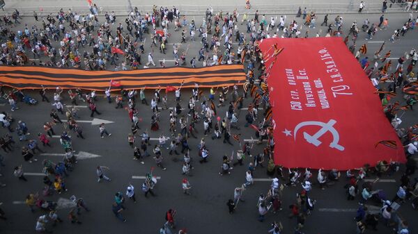 Участники акции Бессмертный полк в Москве несут гигантские георгиевскую ленту и Знамя Победы по Тверской улицы