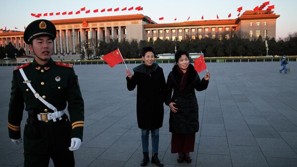 Женщины позируют с национальными флагами на площади Тяньаньмэн в Пекине