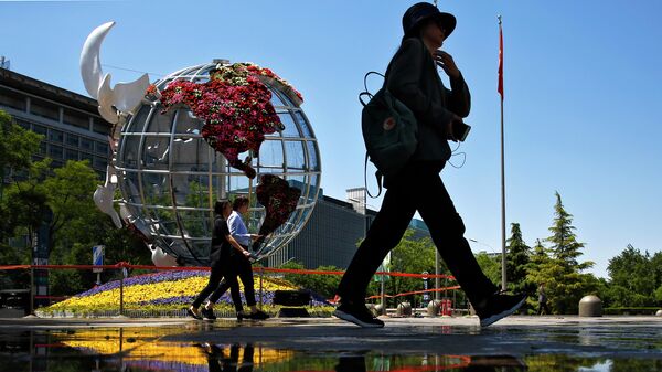 Люди проходят мимо глобуса с изображением США у банка в Пекине