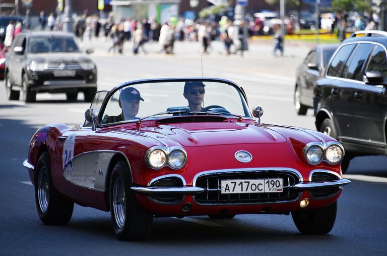 Участники в автомобиле Chevrolet 1962 Corvette GM принимают участие в ралли классических ретро-автомобилей в Москве