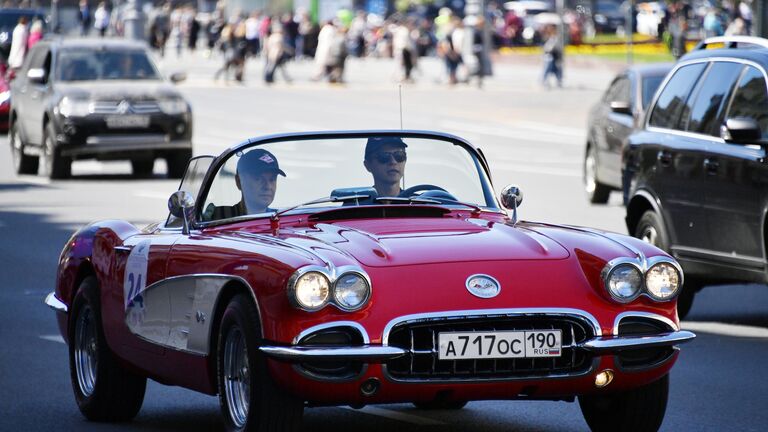 Участники в автомобиле Chevrolet 1962 Corvette GM принимают участие в ралли классических ретро-автомобилей в Москве