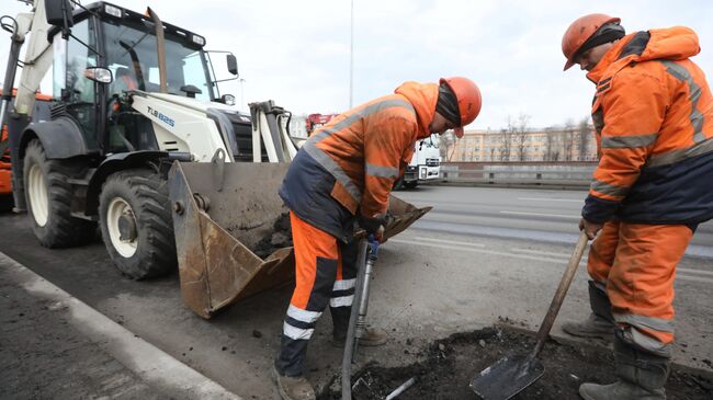 Рабочий бригады демонтирует старое дорожное полотно