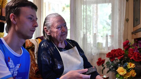 Волонтер помогает в настройке цифровой приставки дома у ветерана Великой Отечественной войны Афросиньи Белозеровой в городе Сочи