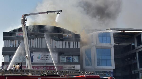 Пожарные во время тушения пожара в торговом центре в индийском городе Сурат штата Гуджарат. 24 мая 2019