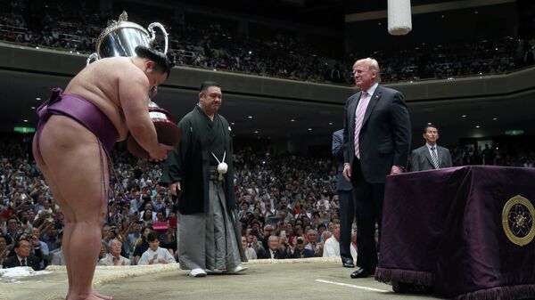 Дональд Трамп вручает кубок президента США победителю летного турнира по сумо в Японии
