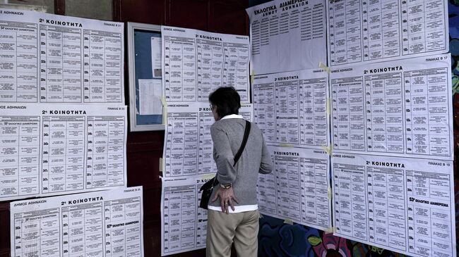 Избиратель знакомится со списками кандидатов в заключительный день голосования на выборах в Европейский парламент на одном их избирательных участков в Афинах. 26 мая 2019