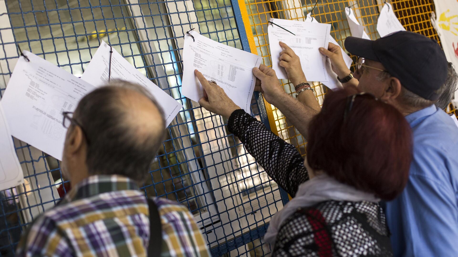 Люди ищут свое имя в избирательном списке на одном из избирательных участков в Мадриде в заключительный день голосования на выборах в Европейский парламент. 26 мая 2019 - РИА Новости, 1920, 04.05.2021