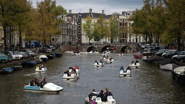 Туристы катаются на прогулочных катамаранах по каналу в центре Амстердама