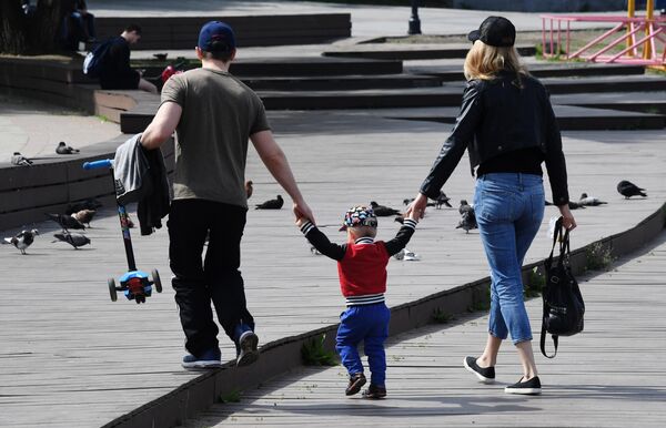 Семейная пара с ребенком гуляют по набережной Спортивной гавани во Владивостоке