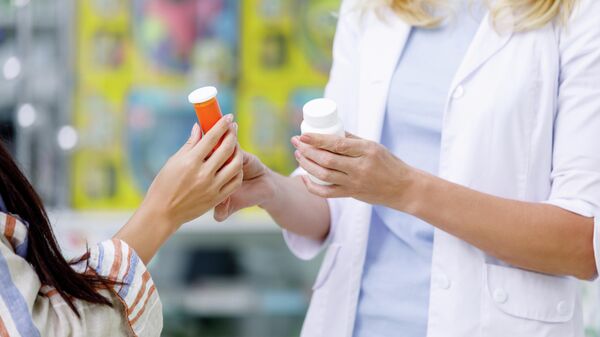 Фармацевт выдает лекарства покупателю в аптеке