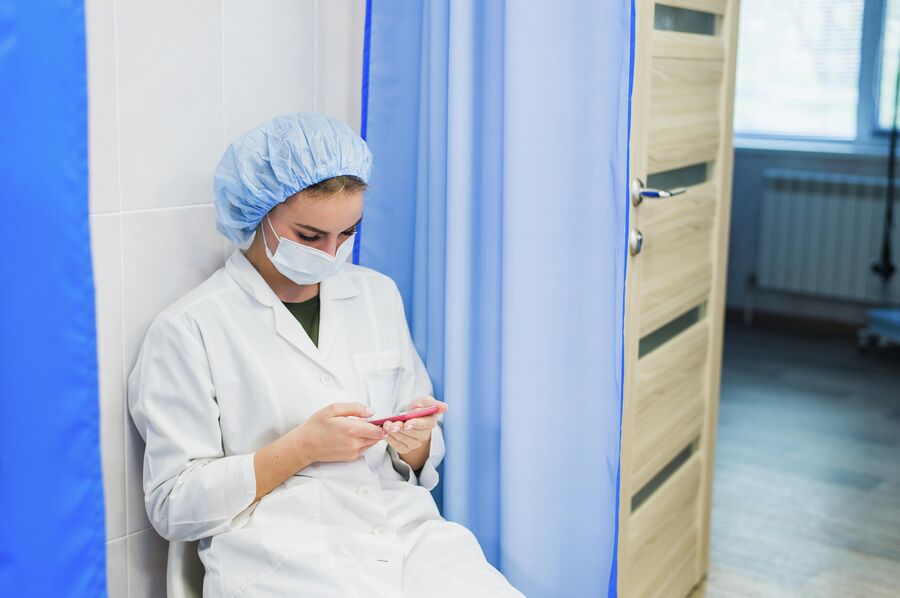 Медсестра с мобильным телефоном во время перерыва. Иллюстративное изображение. 