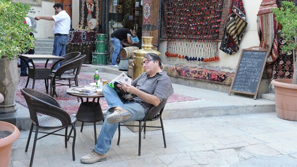 Житель Баку читает газету в уличном кафе в Старом городе