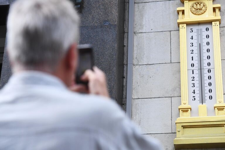 Мужчина фотографирует термометр на здании Государственной Думы РФ в Москве