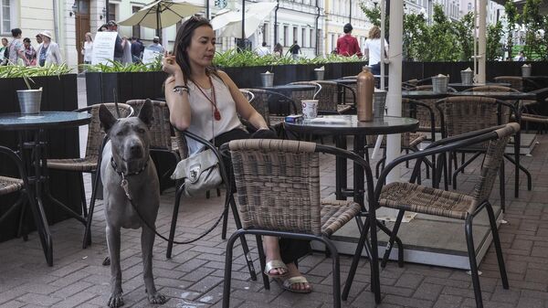 Посетительница с собакой на летней веранде кафе на улице Арбат в Москве