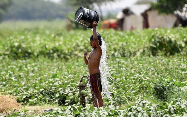 Мальчик поливает себя водой во время жары в Нью-Дели