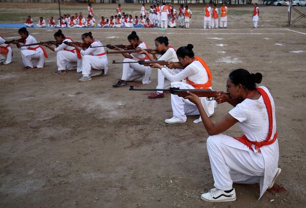 Члены Durga Vahini, националистической организации Вишва хинду паришад демонстрируют свои навыки самообороны с огнестрельным оружием