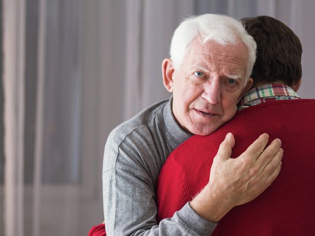 Пожилой мужчина обнимает сына