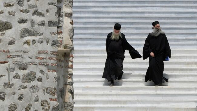 Священнослужители на лестнице здания Священного Кинота Святой Горы в городе Карее
