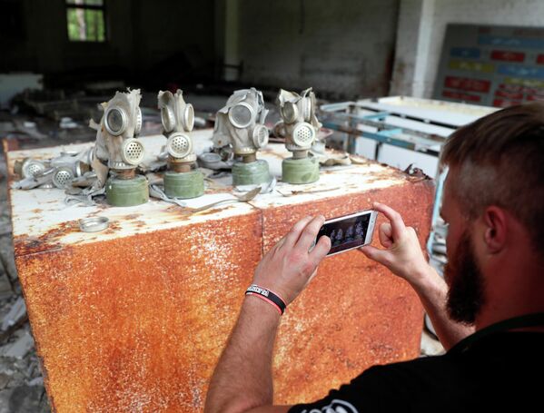  Турист фотографирует противогазы на бывшей базе советской армии, недалеко от Чернобыльской АЭС, Украина 