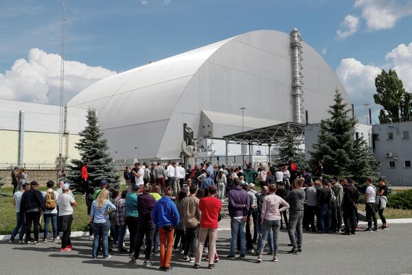 Туристы возле Нового безопасного конфайнмента над старым саркофагом, покрывающим поврежденный четвертый реактор на Чернобыльской АЭС
