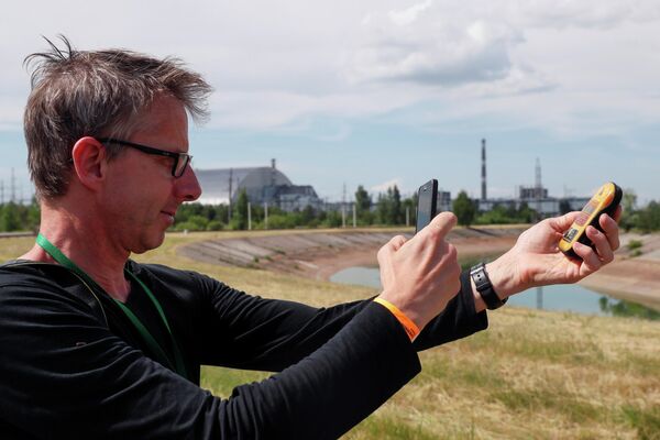 Турист фотографирует дозиметр возле Нового безопасного конфайнмента над старым саркофагом, покрывающим поврежденный четвертый реактор на Чернобыльской АЭС
