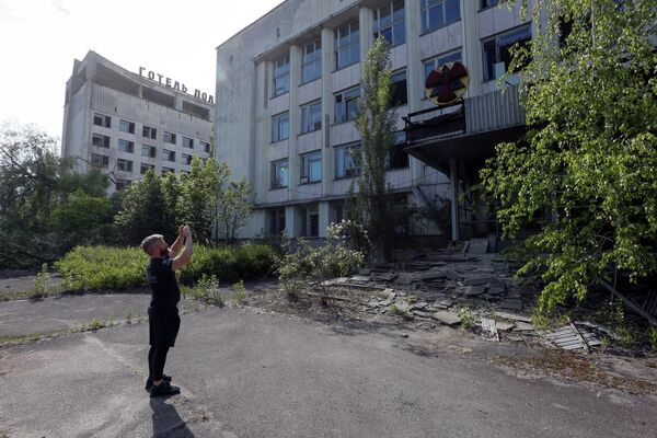 Турист фотографирует здание в заброшенном городе Припять, рядом с Чернобыльской АЭС, Украина
