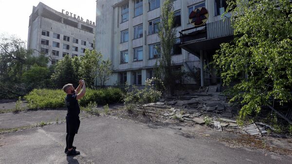 Турист фотографирует здание в заброшенном городе Припять, рядом с Чернобыльской АЭС, Украина