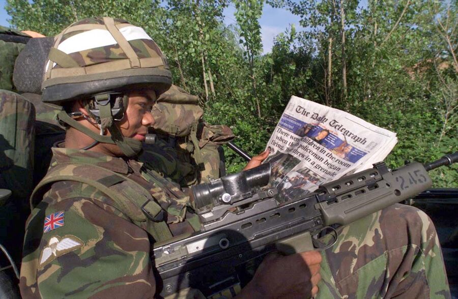 Британский солдат-гуркх читает газету на КПП НАТО в Приштине