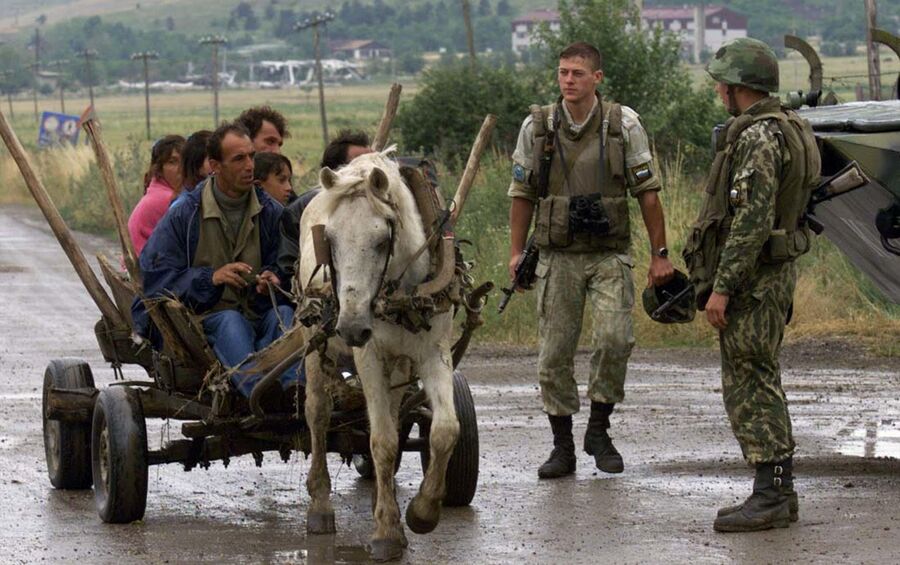 Этнические албанцы проезжают мимо российских военных, дислоцированных у аэропорта Слатина в Приштине 