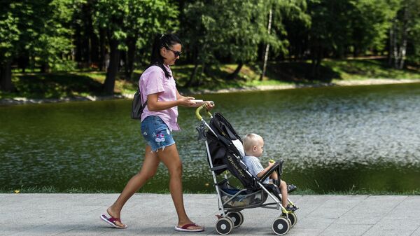 Женщина с ребенком гуляет по набережной пруда в парке