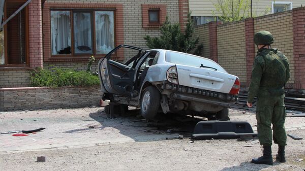 Военнослужащий ДНР у автомобиля, поврежденного в результате артиллерийского обстрела города Докучаевск Донецкой области